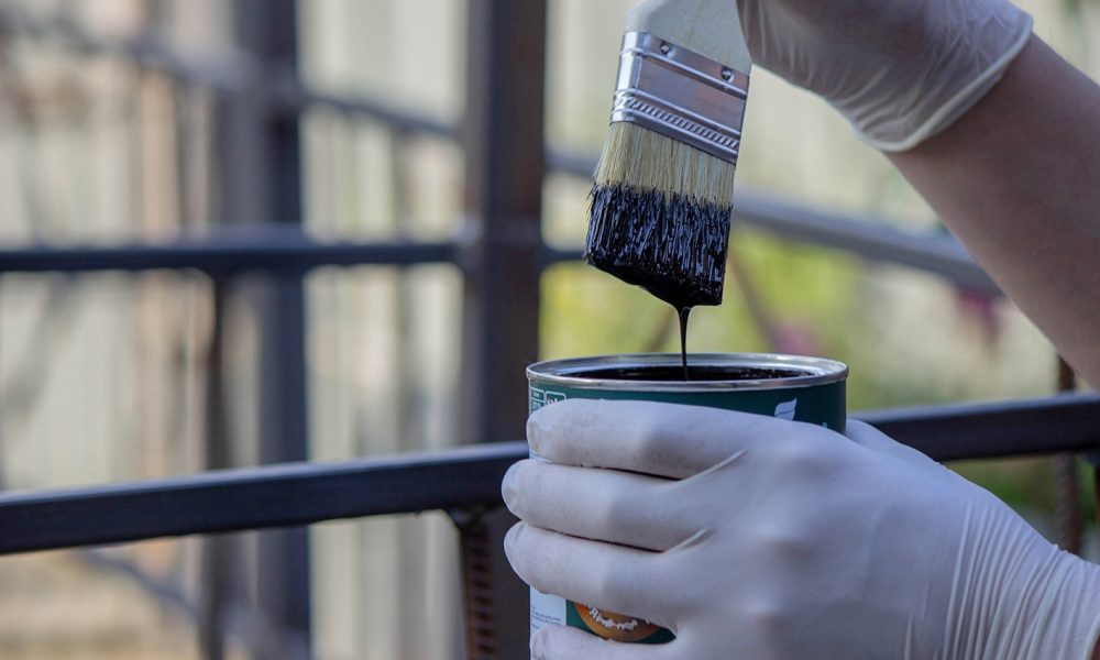 close-up of a hand painting a metal pipe. Selective focus.