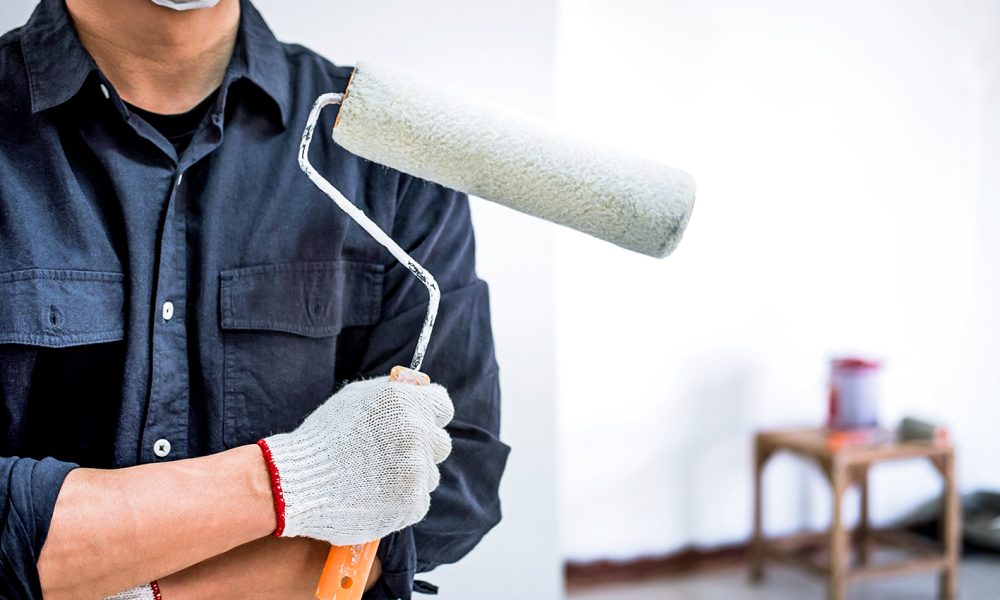 Male Painter with arm crossed holding paint roller, Interior wor