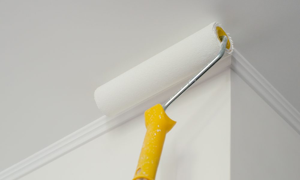Paint roller with yellow handle. Ceiling and wall painting process. White background. Copy space