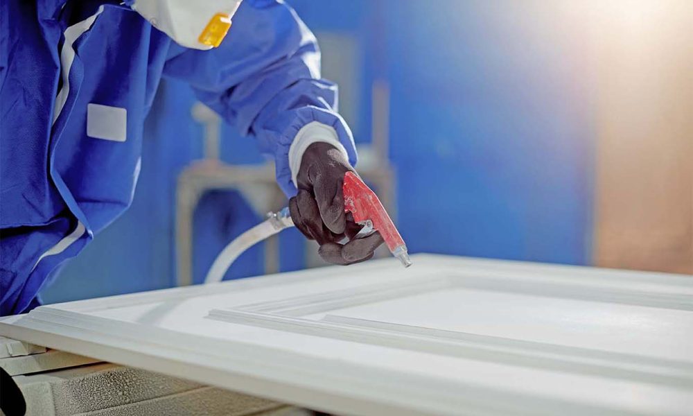 Close-up of worker spraying paint over processed wood at product